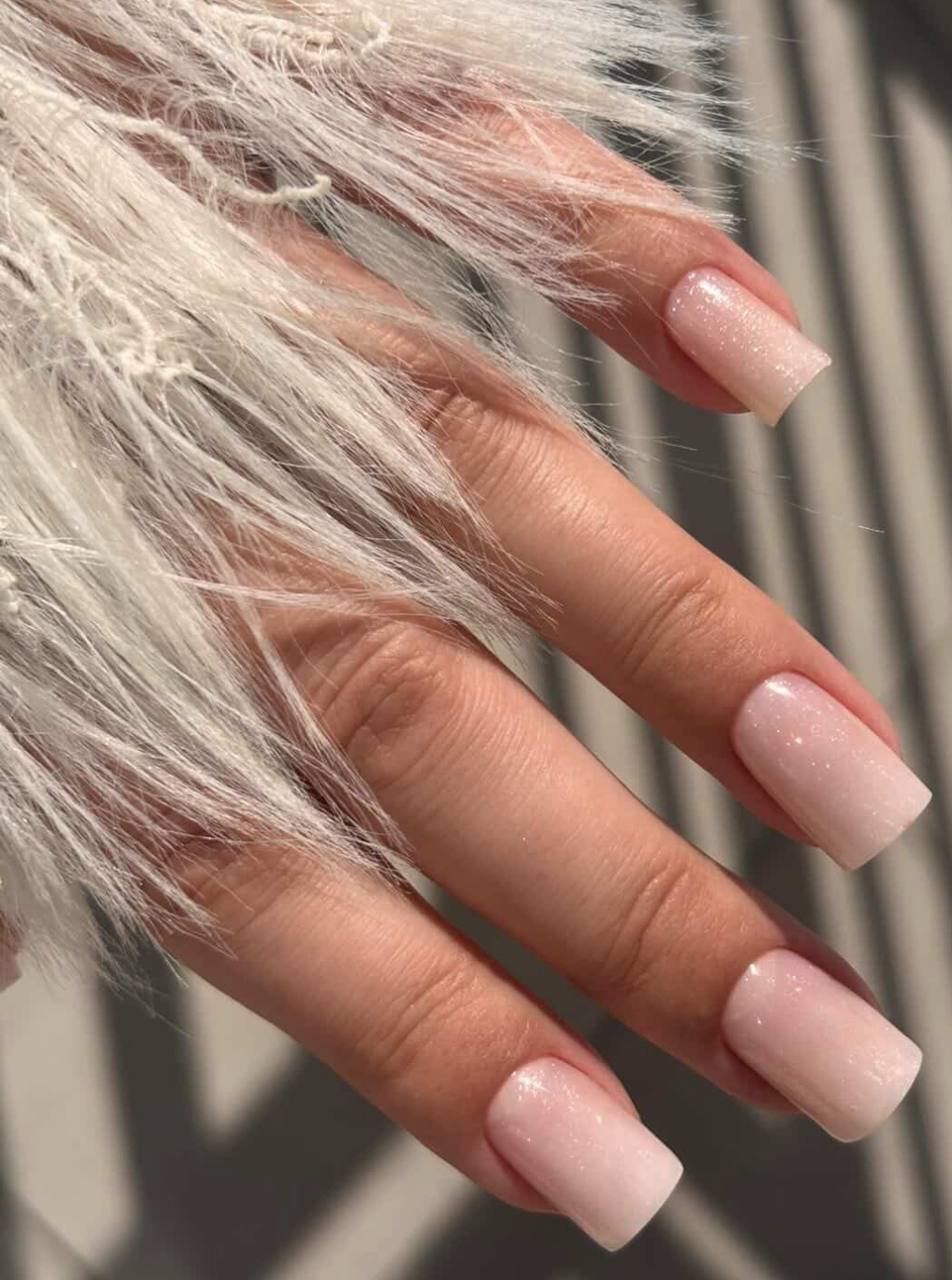 Manicure żelowy w kolorze mlecznego różu z brokatowym ombre